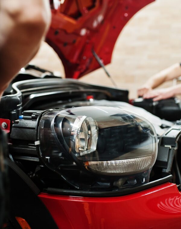 car-protection-with-special-films-2025-02-10-10-26-12-utc-min Neil Arnold Tyres And Autos Mechanic inspecting damaged headlight of red car