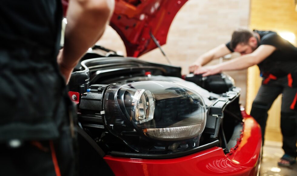 car-protection-with-special-films-2025-02-10-10-26-12-utc-min Neil Arnold Tyres And Autos Mechanic inspecting damaged headlight of red car