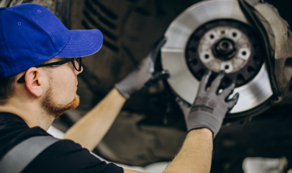 26909 Neil Arnold Tyres And Autos Mechanic inspecting brake rotor during car repair.