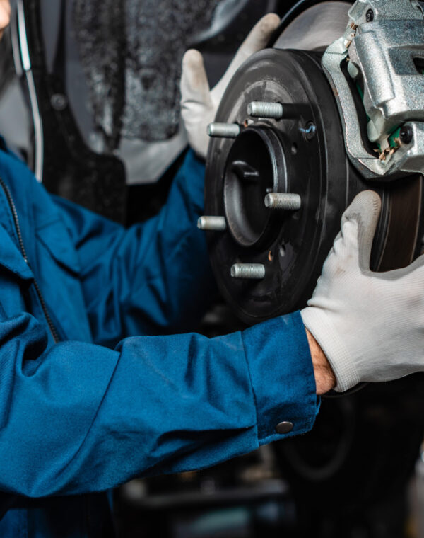 Breaks Neil Arnold Tyres And Autos Mechanic inspecting car brake rotor and caliper during auto repair.