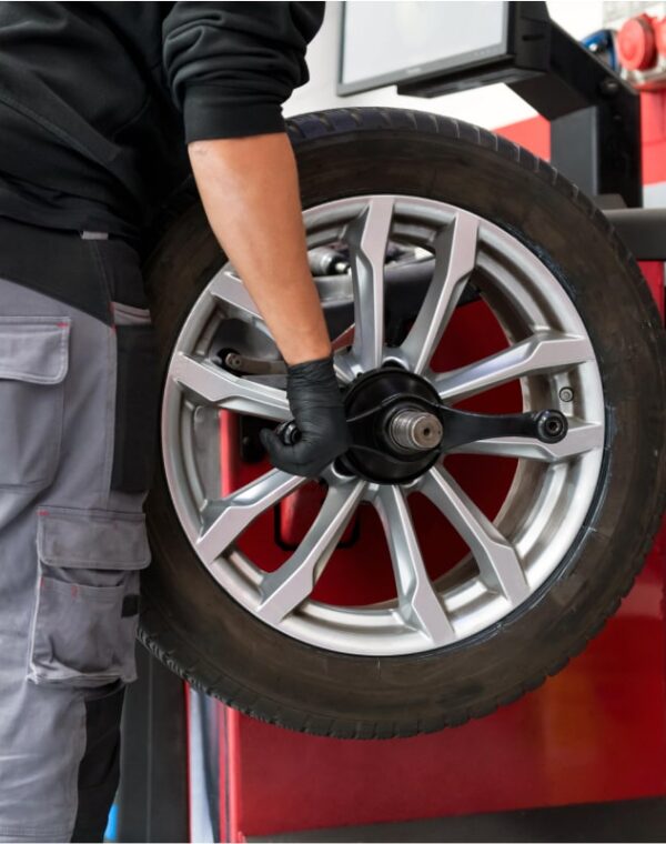 Wheel Balancing for a Smoother & Safer Ride-min Neil Arnold Tyres And Autos Mechanic mounting tire on wheel balancing machine