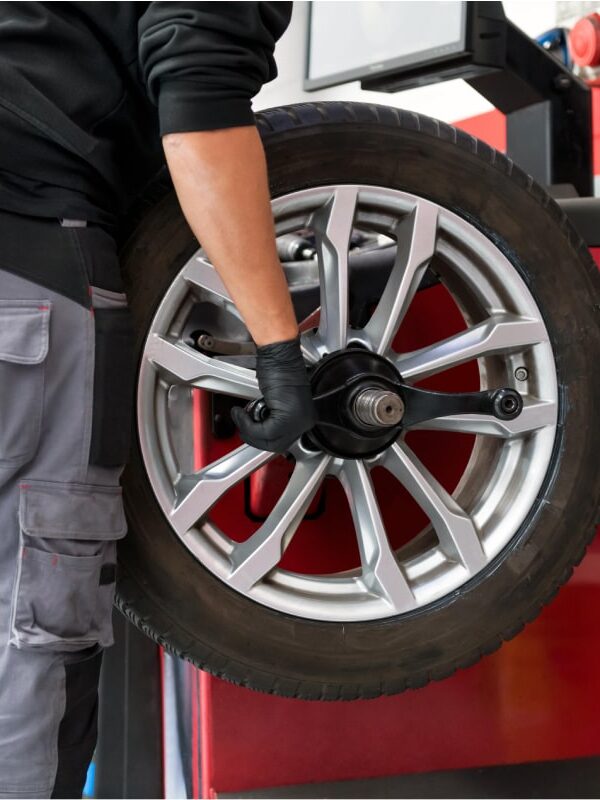 Wheel Balancing for a Smoother & Safer Ride-min Neil Arnold Tyres And Autos Mechanic mounting tire on wheel balancing machine