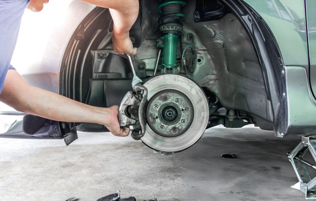Neil Arnold Tyres And Autos Mechanic repairing car brakes with wrench