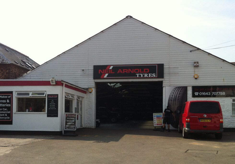 Neil Arnold Tyres shop exterior with red van parked outside.